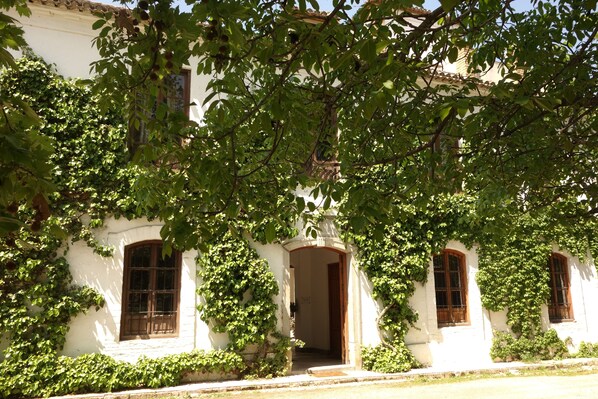 A building with arched windows and a doorway, surrounded by lush greenery. - Charming rural house with swimming pool 3 km from the city of Granada. Parking (Camino Viejo de Cuéllar)