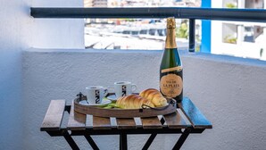 A table with a bottle of La Plata wine, two cups, and a croissant on a balcony overlooking a coastal town. - 419 Beautiful Summerland Studio, Wi-Fi sat.Tv (Los Cristianos)