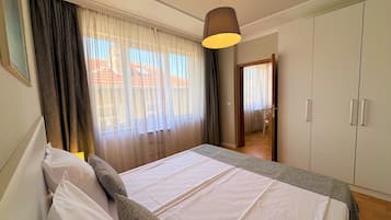 Une chambre à coucher avec un lit, des rideaux, un luminaire suspendu et une armoire.