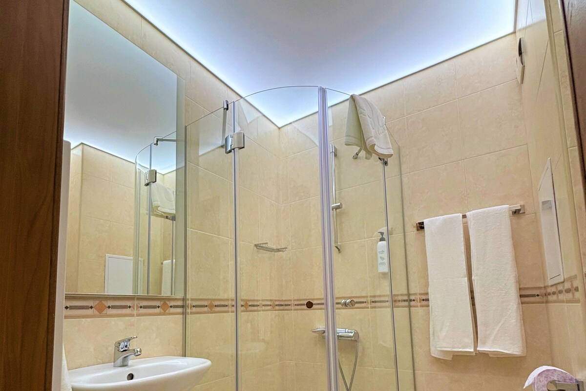 A modern bathroom with a glass-enclosed shower, a sink, and a toilet.