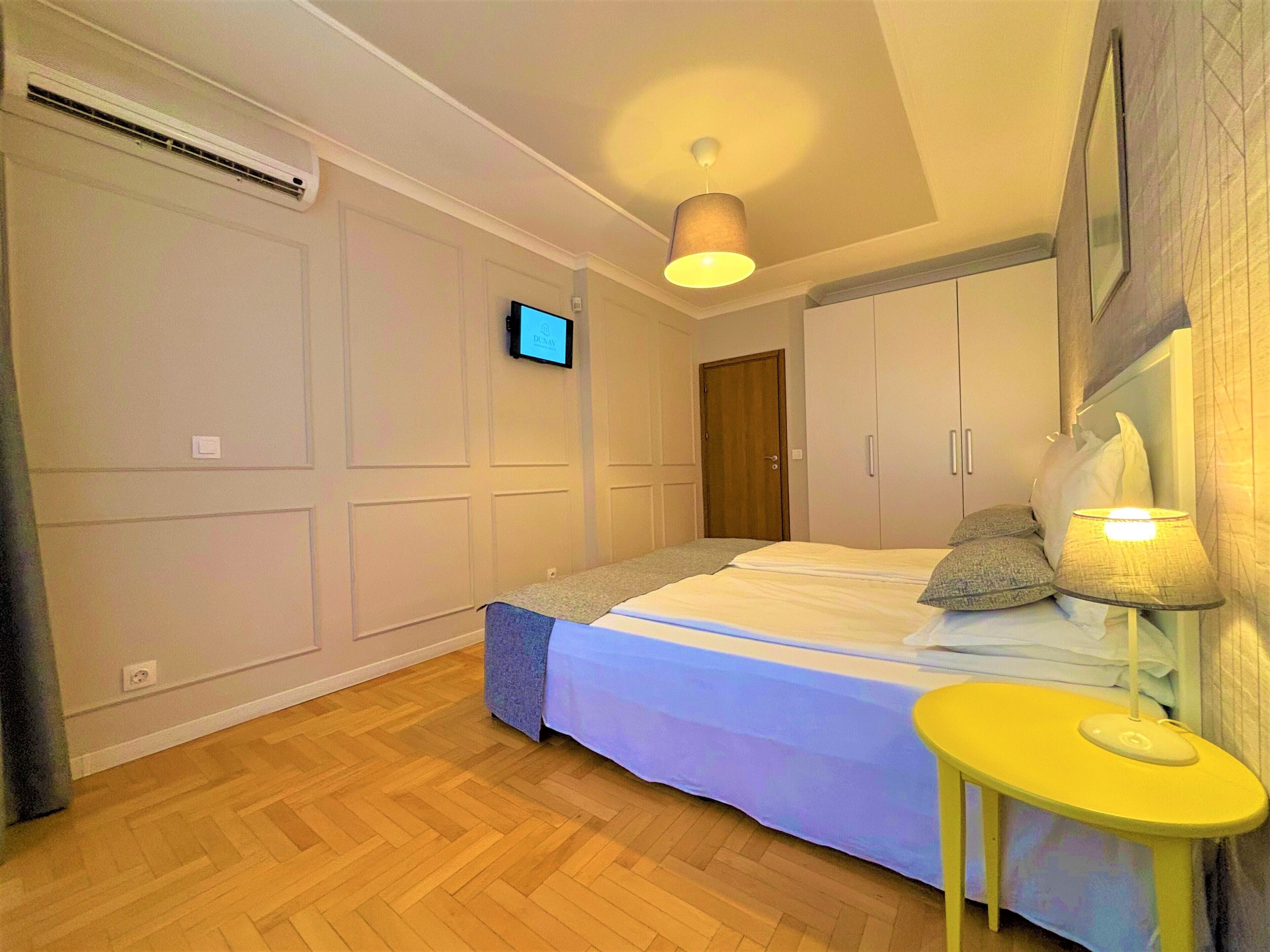 A bedroom with a bed, a bedside table, a TV, and a wardrobe.