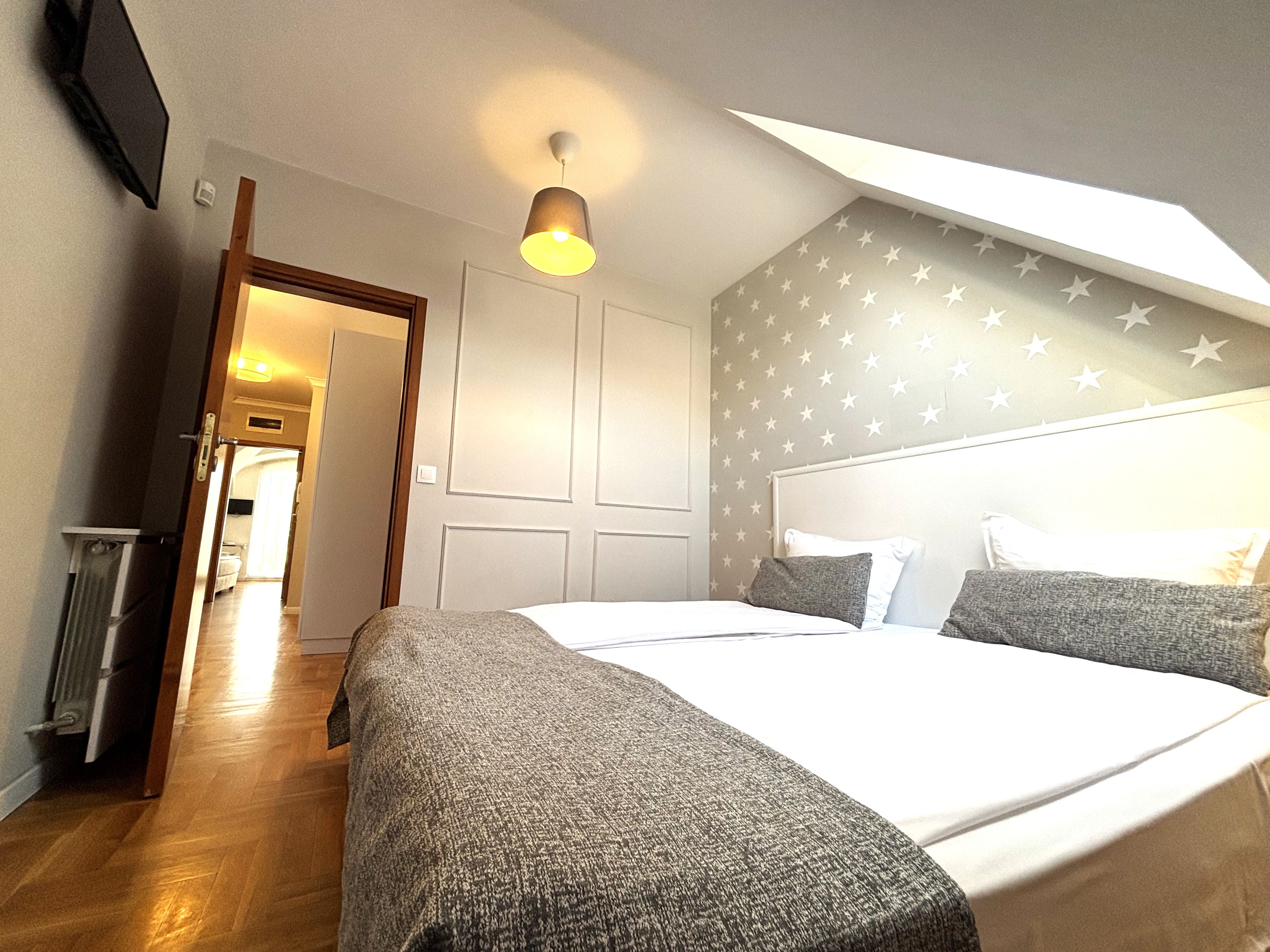 Une chambre d’hôtel avec un lit, un luminaire au plafond, une porte et un mur orné de motifs en forme d’étoiles.