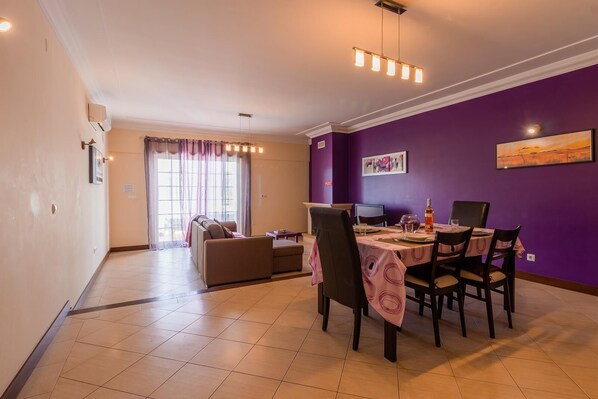 A dining area with a table set for four, a sofa, and a window with curtains.