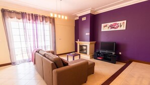 A living room with a sofa, a fireplace, a television, and a painting on the wall. - 15min walk from Albufeira Old Town, Free wifi, Air Conditioning (Albufeira)