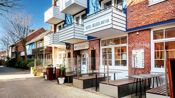 A hotel with a brick facade, outdoor seating, and a sign for 'Hotel Helgolandia'. - Hotel Helgolandia (Helgoland)