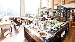A buffet setup with multiple serving stations, a long counter with various dishes, and a seating area with tables and chairs. - Sono Felice Vivaldi Park (Hongcheon)