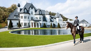 A large, white, multi-story building with a pond in front, likely a hotel or estate. - Sono Felice Vivaldi Park (Hongcheon)