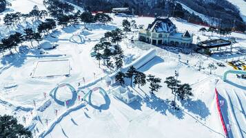 A snow-covered ski resort with a large building, ski lifts, and marked trails.