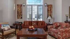 A living room with a large window, a sofa, a chair, a coffee table, and a lamp.