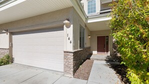 A two-story house with a white garage door, a stone base, and a red door.