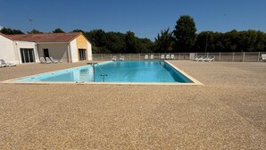 Una piscina con sillas de descanso y un edificio al fondo.