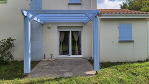 Una casa de dos plantas con un porche cubierto y puerta corrediza de vidrio.