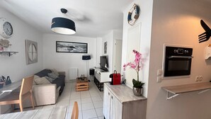 Una cocina moderna con horno integrado, un comedor con mesa y sillas de madera, un sofá y una mesita auxiliar.