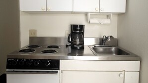 Eine kleine Küche mit Herd, Kaffeemaschine und Spüle.