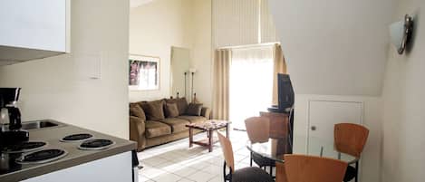 A compact living space with a kitchenette, a dining area, and a seating area with a sofa and chairs.