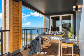 Eine Holzterrasse mit Tisch und Stühlen mit Blick auf ein Gewässer.