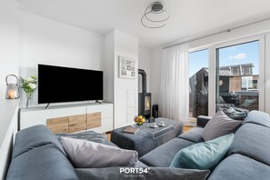 Una sala de estar moderna con un televisor de pantalla plana, una chimenea y un sofá grande.
