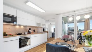 Una cocina moderna con armarios blancos, un microondas Bosch y una encimera de madera.