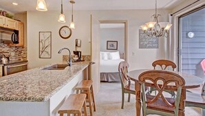 A kitchen with a granite countertop, wooden stools, and pendant lights. - 1 Bedroom Ski in Condo Only One Block From Historic Downtown, Shopping, Restaurants and Entertainment (Breckenridge)