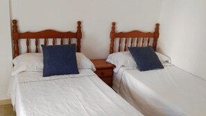 Two single beds with wooden headboards, white bedding, and blue pillows. - Azul Rentals Benidorm flat, walk to beach, bars.. (Benidorm)