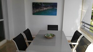 A dining area with a table and four chairs, a bowl on the table, and a painting on the wall. - Azul Rentals Benidorm flat, walk to beach, bars.. (Benidorm)