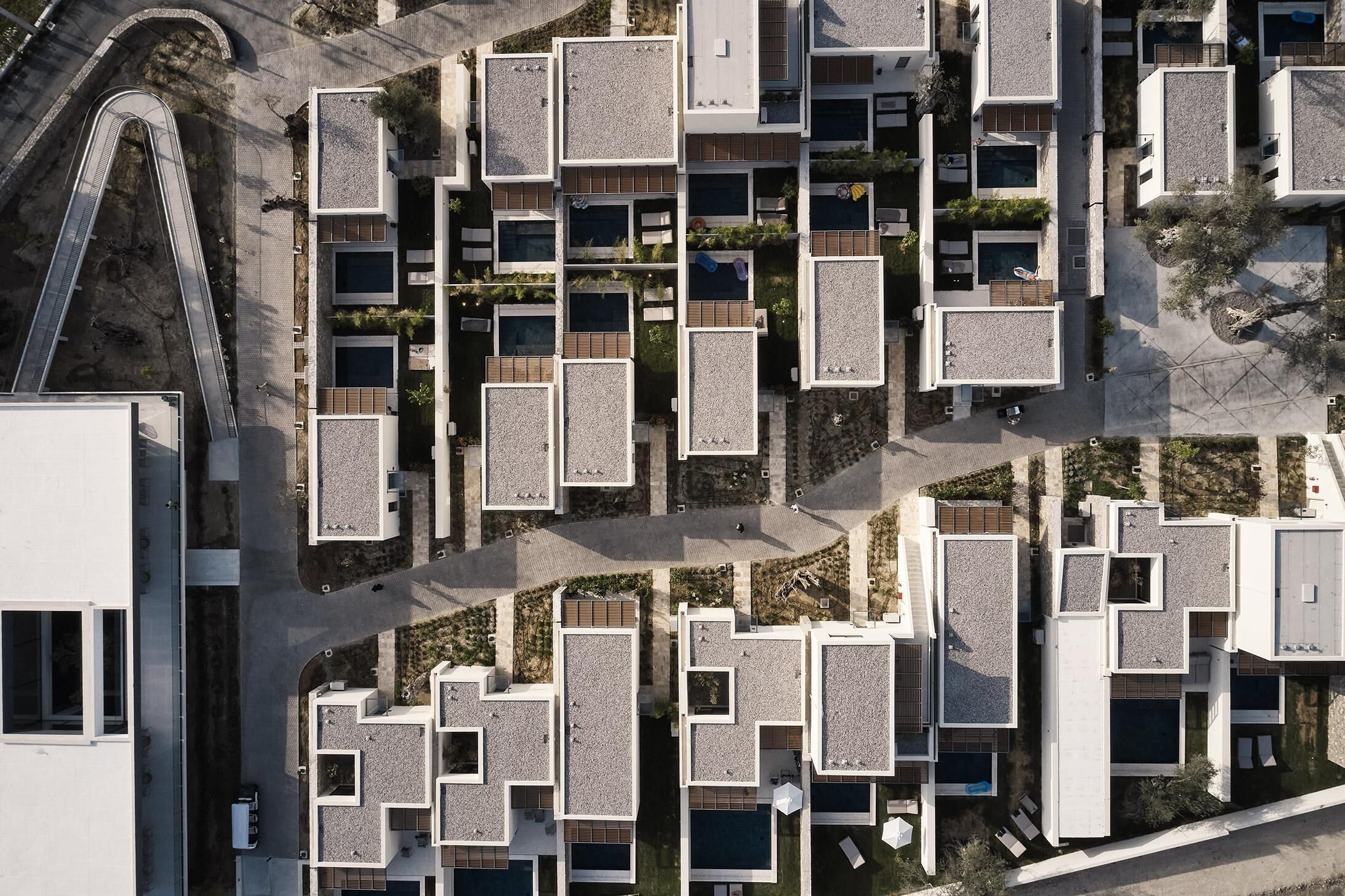 Vista aérea de un complejo residencial moderno con varios edificios, pasarelas interconectadas y zonas ajardinadas.