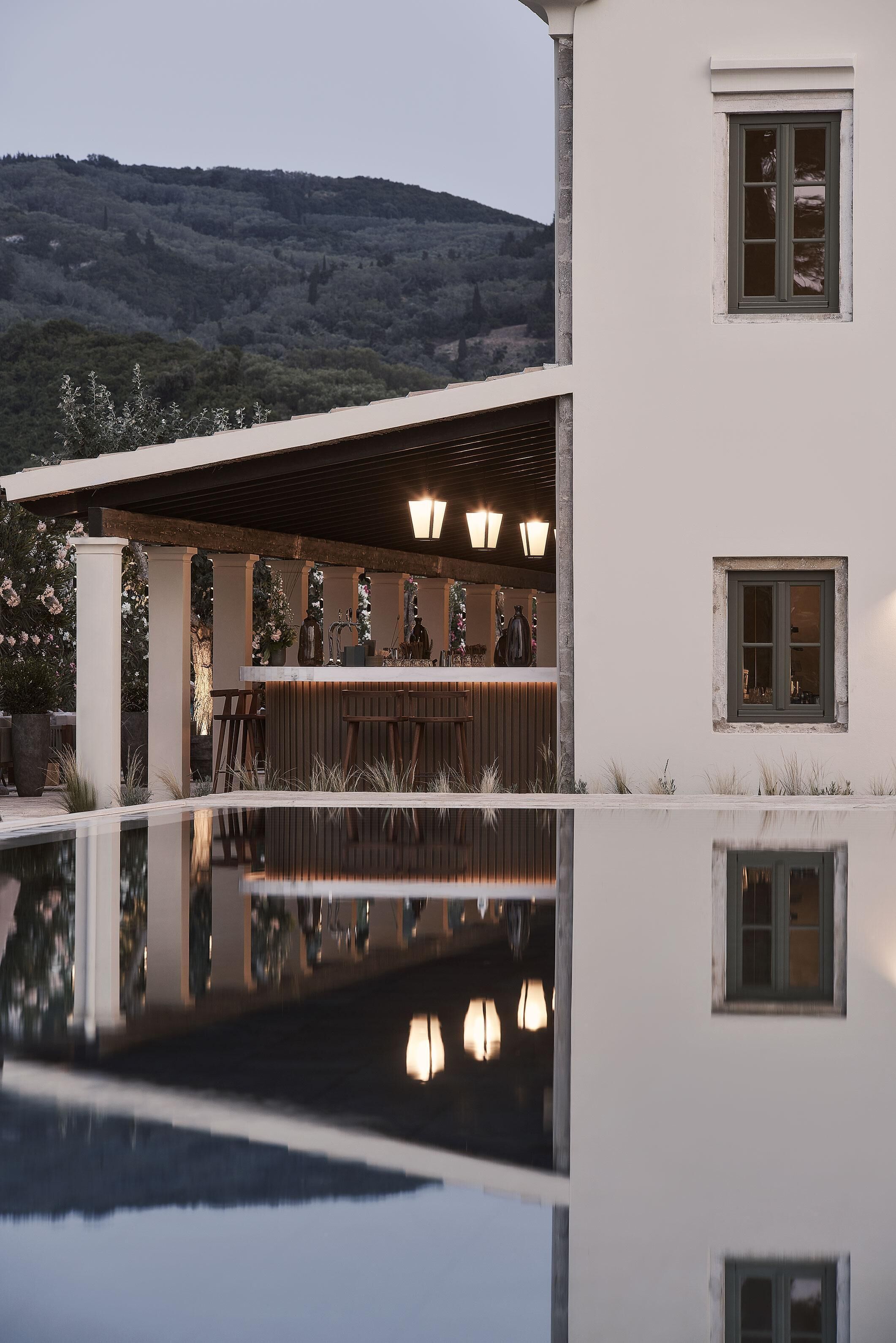 Un edificio moderno con zona bar, piscina e vista su un paesaggio collinare.