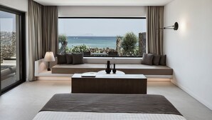 A modern bedroom with a large bed, a sofa bed, a coffee table, and a view of the sea. - The Olivar Suites (Corfu)