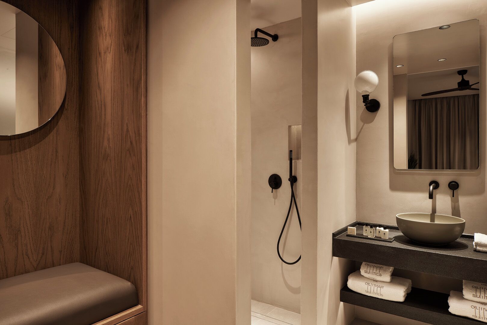 Un bagno moderno con un mobile lavabo in legno, uno specchio rotondo, un lavabo a incasso e uno spazio doccia.