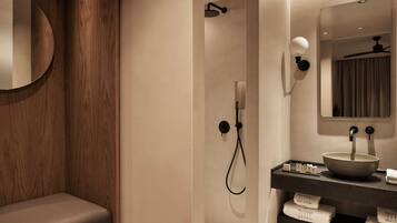 Un bagno moderno con un mobile lavabo in legno, uno specchio rotondo, un lavabo a incasso e uno spazio doccia.