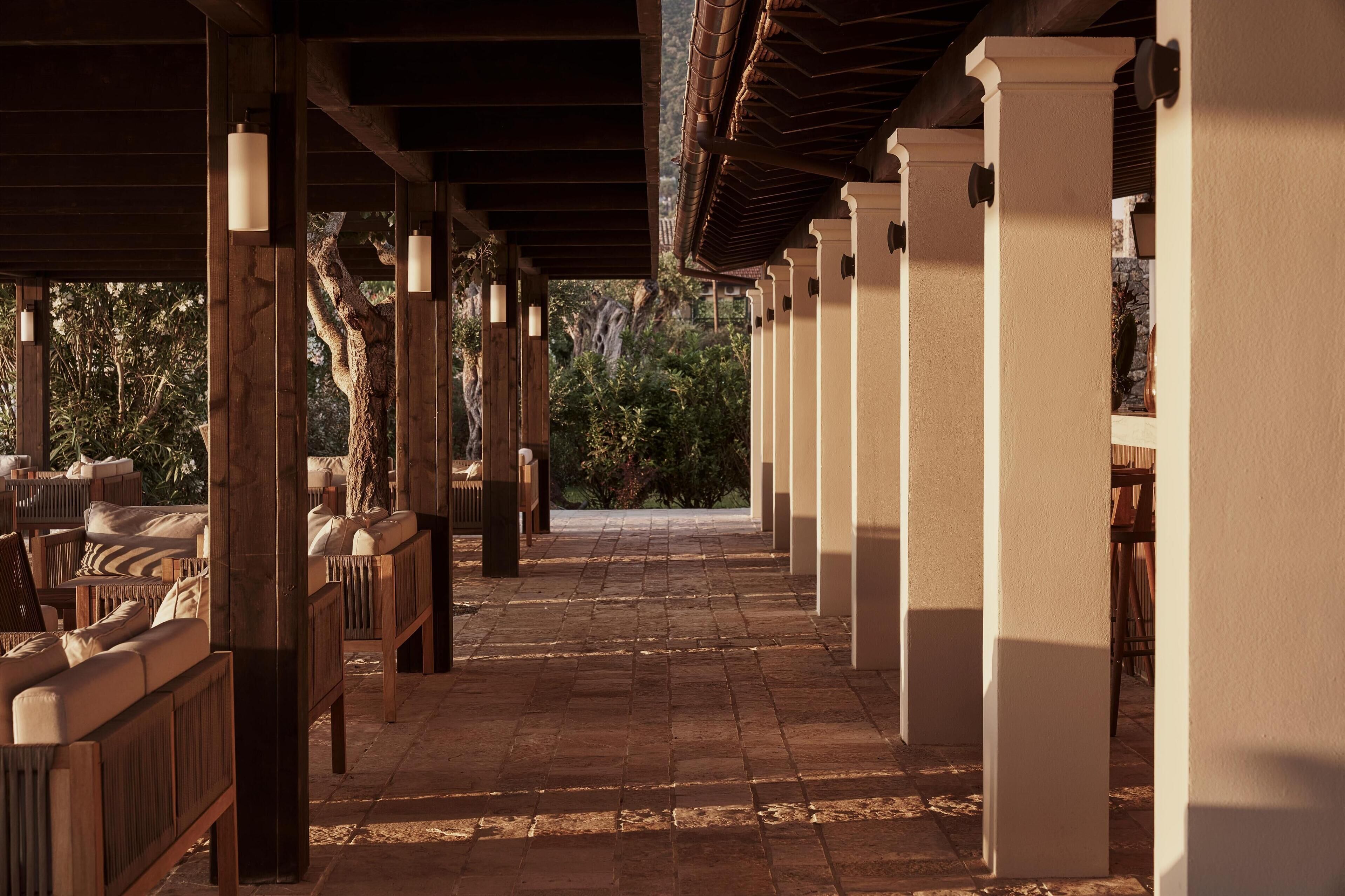Un espacio al aire libre cubierto con mobiliario de madera y columnas.