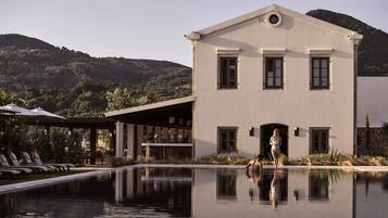 A pool area with lounge chairs and a building with a large window and a door.