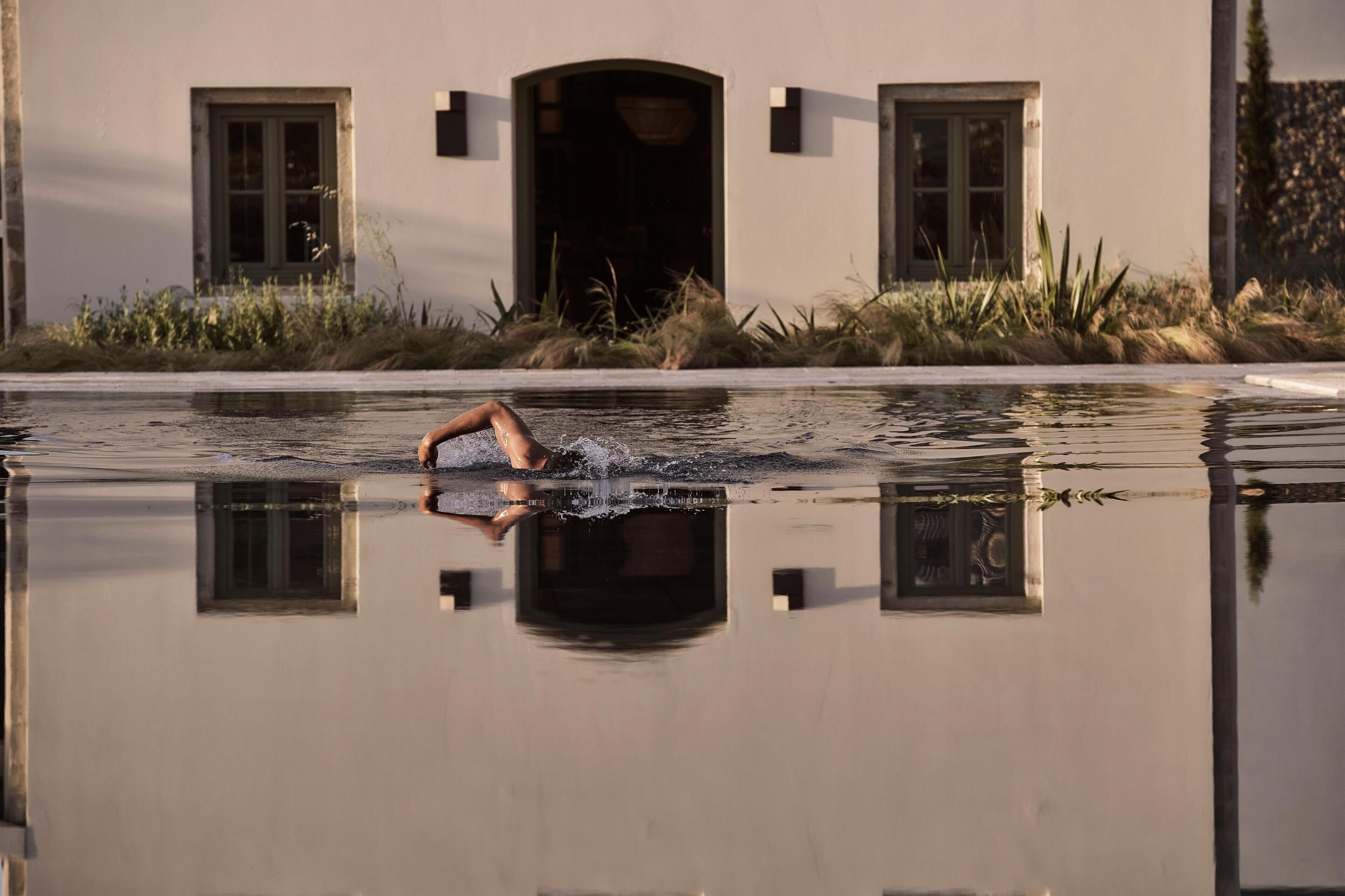 Una persona nadando en una piscina con un edificio al fondo.
