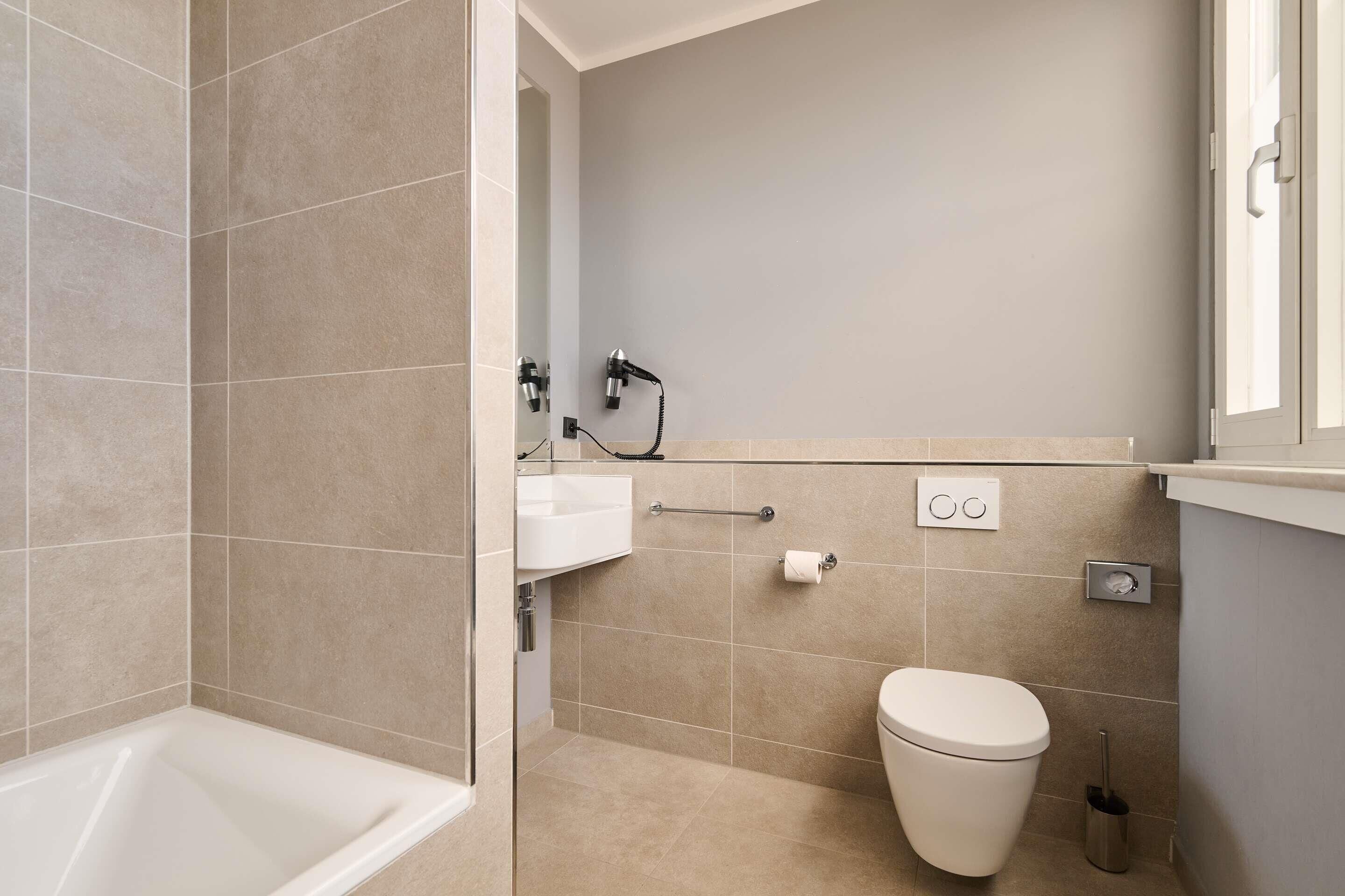 Un baño moderno con bañera, inodoro y un secador de manos montado en la pared.