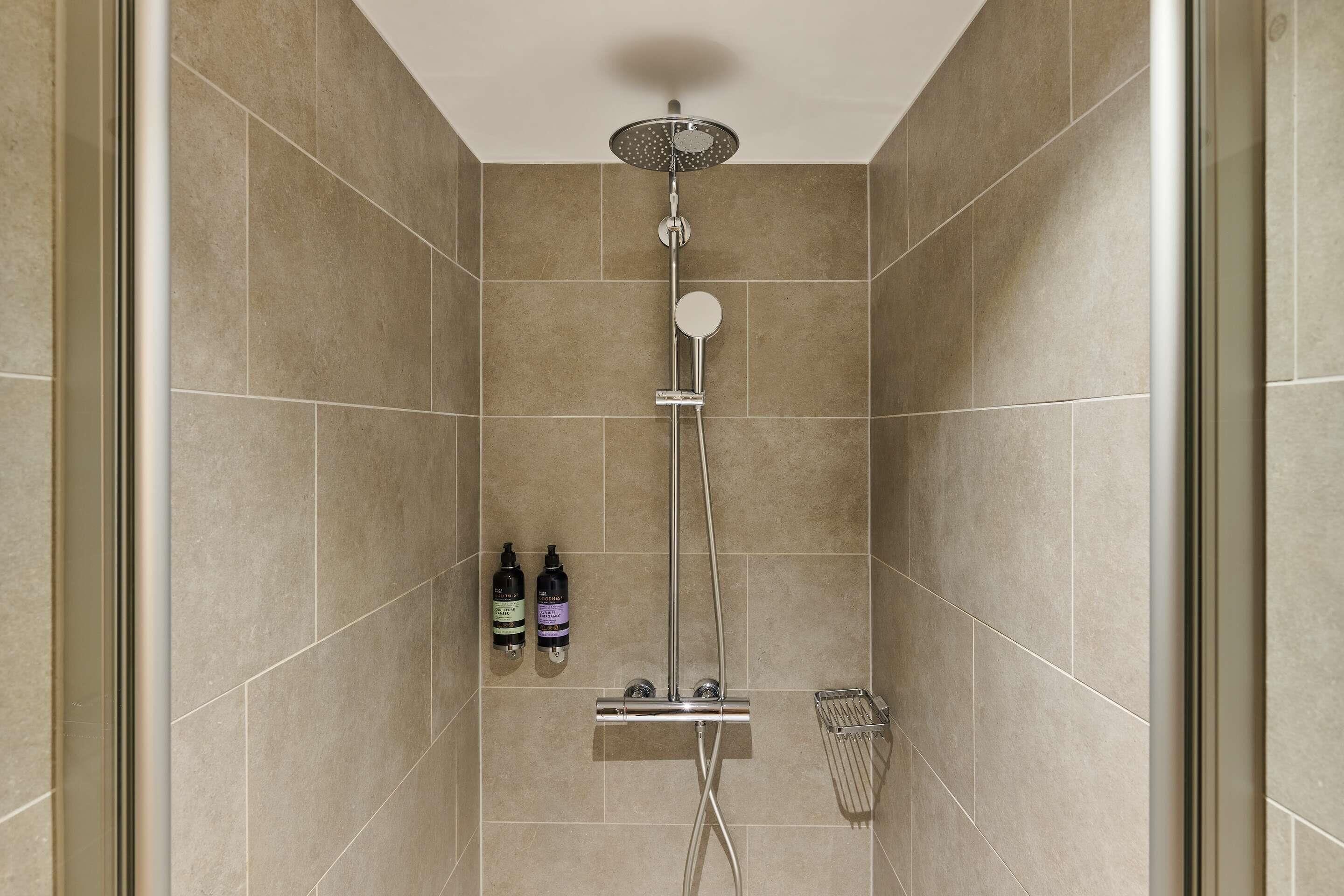 Une douche équipée d’un pommeau de douche à main, d’un robinet mural et d’un pommeau de douche à main.