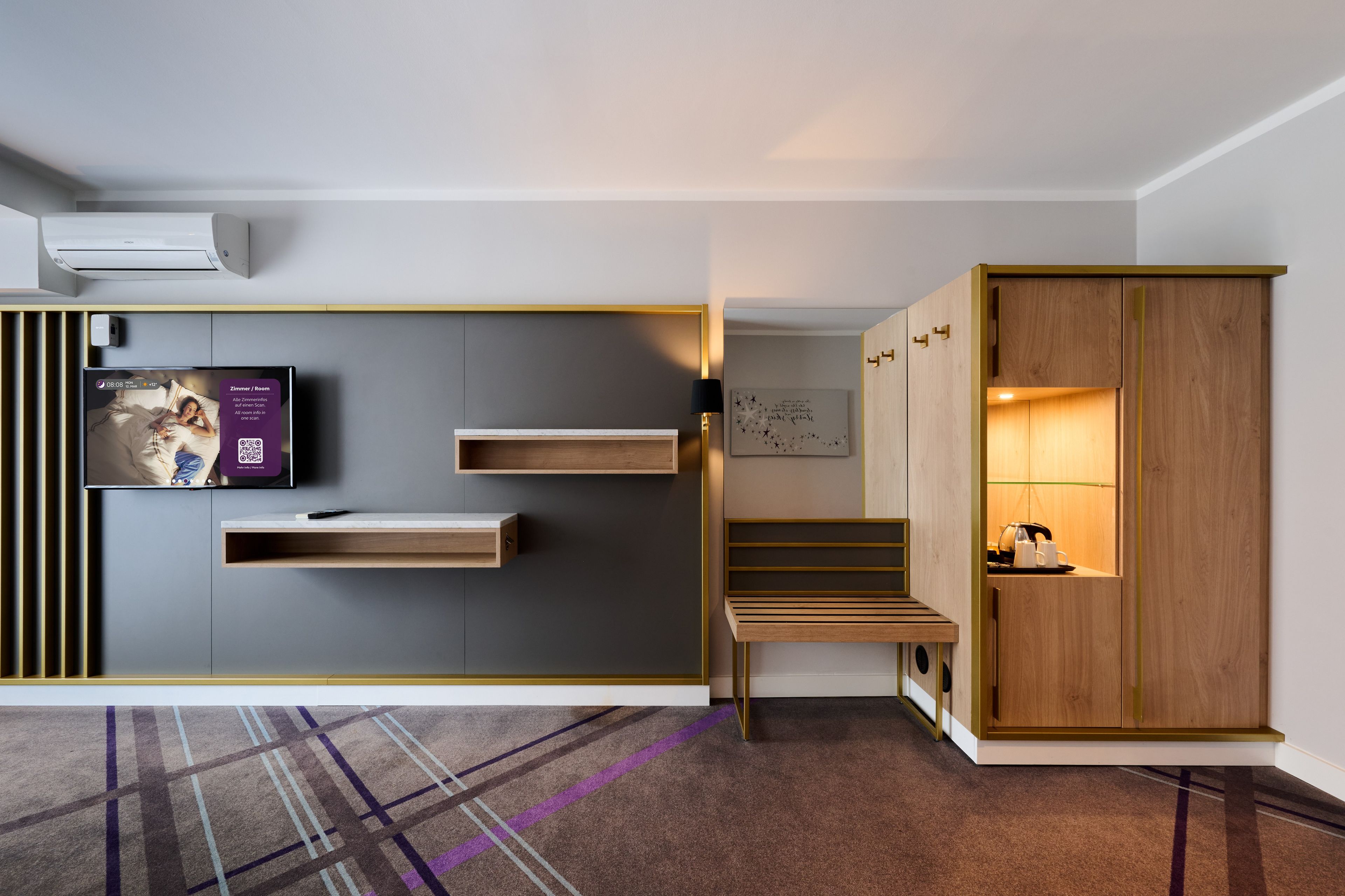 A modern room with a built-in TV, a wooden cabinet, a small table, and a patterned carpet.