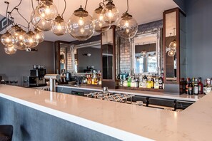 A bar area with a long counter, multiple hanging light fixtures, and a large mirror. - Premier Inn Saarbrücken City Centre (Saarbrucken)