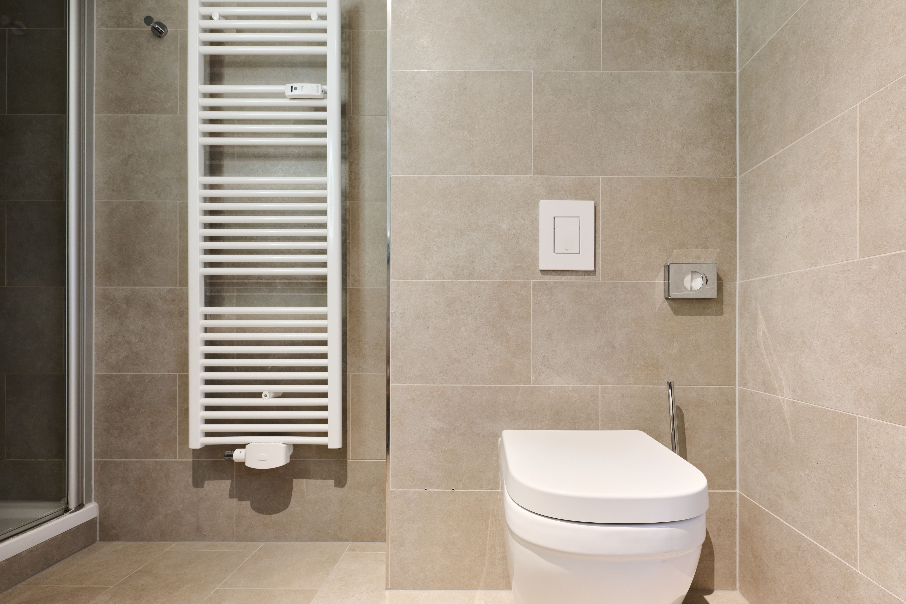 Un baño moderno con inodoro, toallero y un interruptor de luz en la pared.