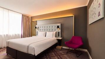 Een hotelkamer met een groot bed, een nachtkastje, een stoel en een wandklok.