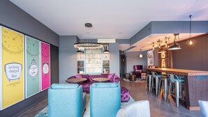 A modern interior with a bar area, seating, and a bookshelf. - Premier Inn Saarbrücken City Centre (Saarbrucken)