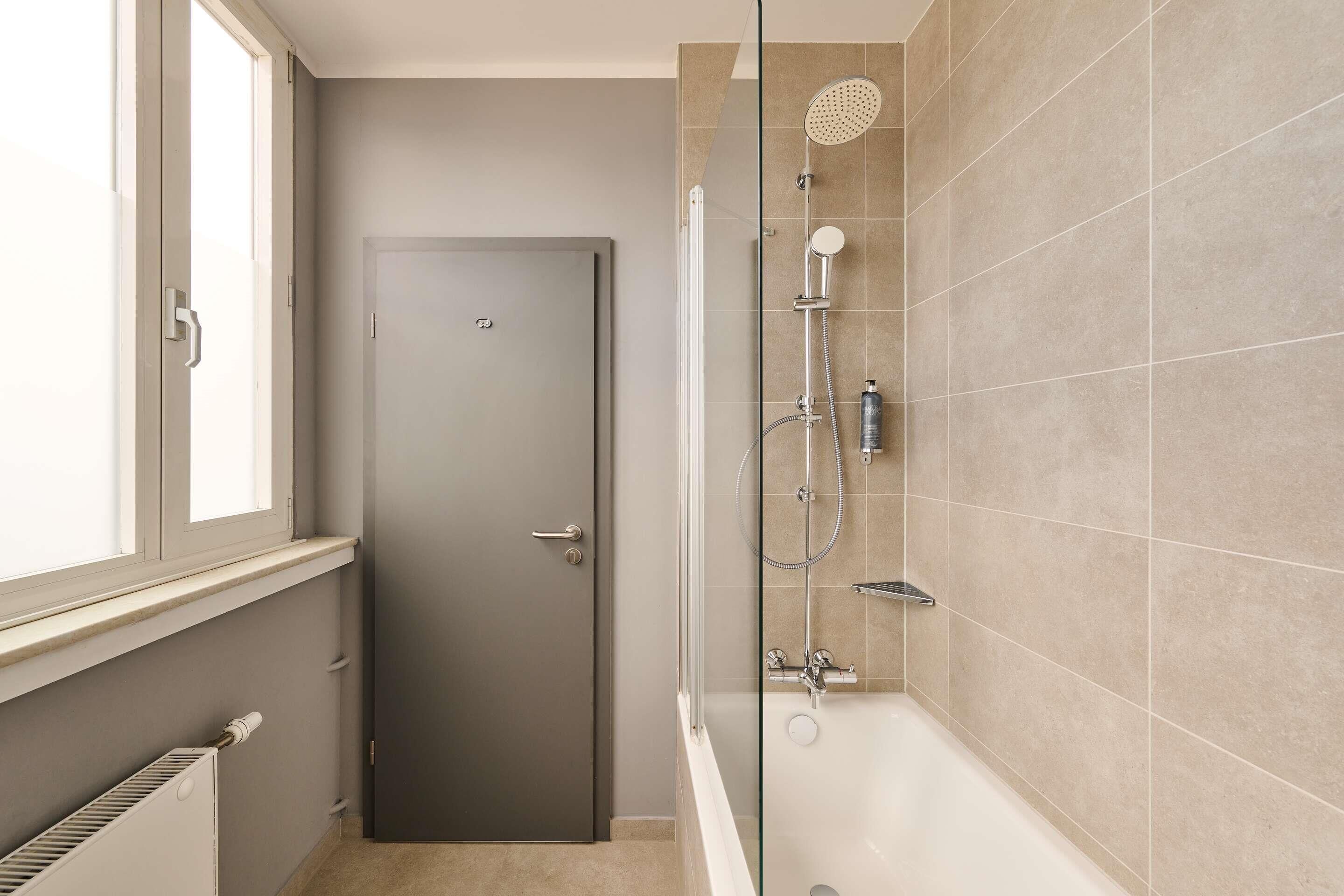 A bathroom with a shower, a door, and a radiator.