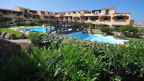 A hotel with a swimming pool, a bridge, and a garden area. - Two-room apartment with air conditioning and swimming pool (Santa Teresa Gallura)