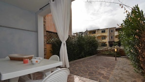 A patio with a table and chairs, a basket, and bowls. - Two-room apartment with air conditioning and swimming pool (Santa Teresa Gallura)