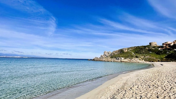 A beach with clear water, a sandy shore, and rocky terrain with buildings. - Two-room apartment with air conditioning and swimming pool (Santa Teresa Gallura)