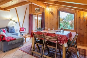 A cozy room with a dining table set for four, a sofa, and a window with curtains.