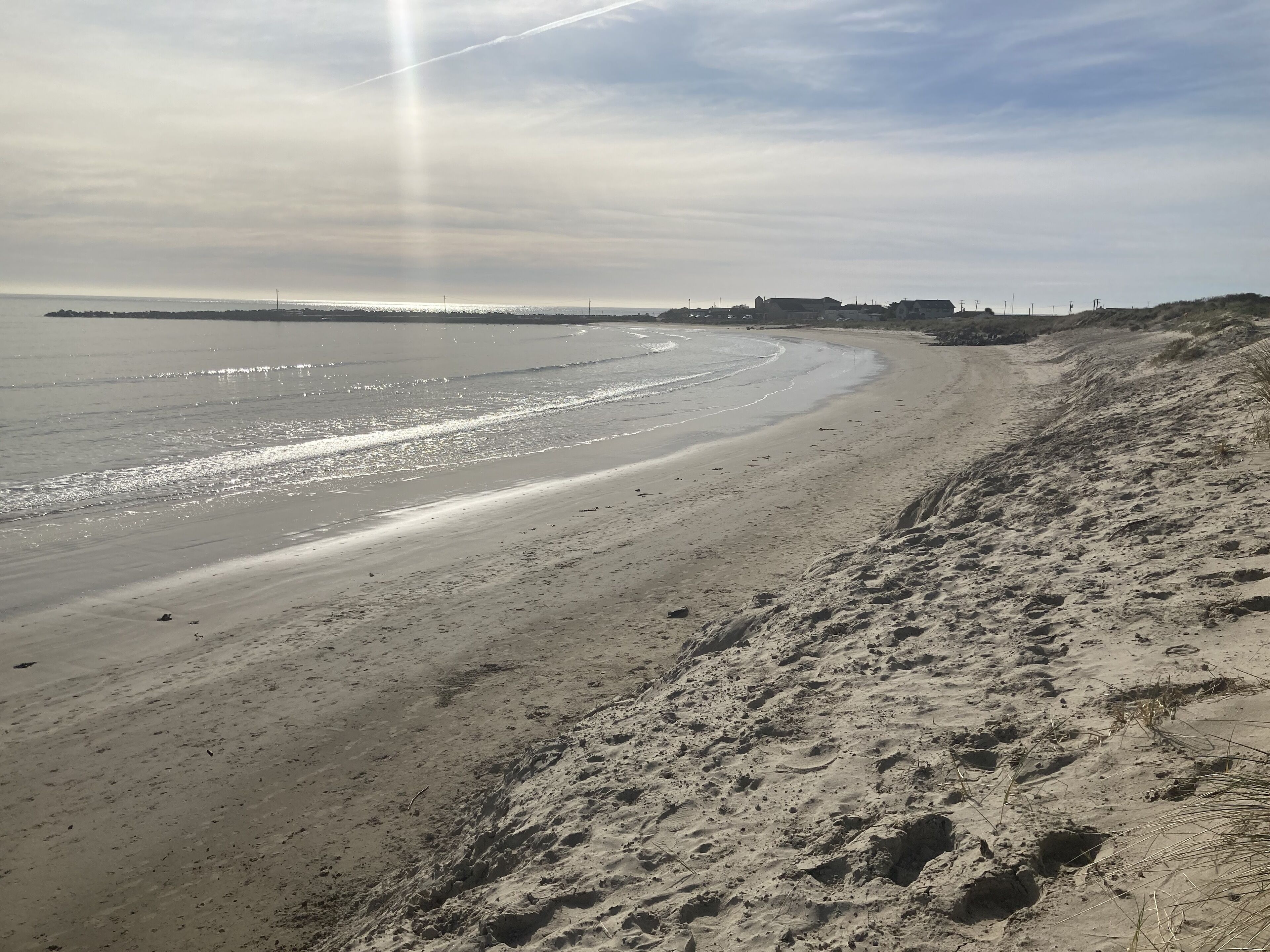 Ein Strand mit breitem Sandufer und freiem Blick auf den Ozean.