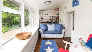 Una habitación acogedora con un sofá azul, un cuenco de madera en el alféizar de la ventana y un tapete azul con diseño de estrellas.