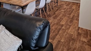 Eine moderne Küche mit weißen Schränken, einem Holzespeisetisch und einem schwarzen Ledersofa.