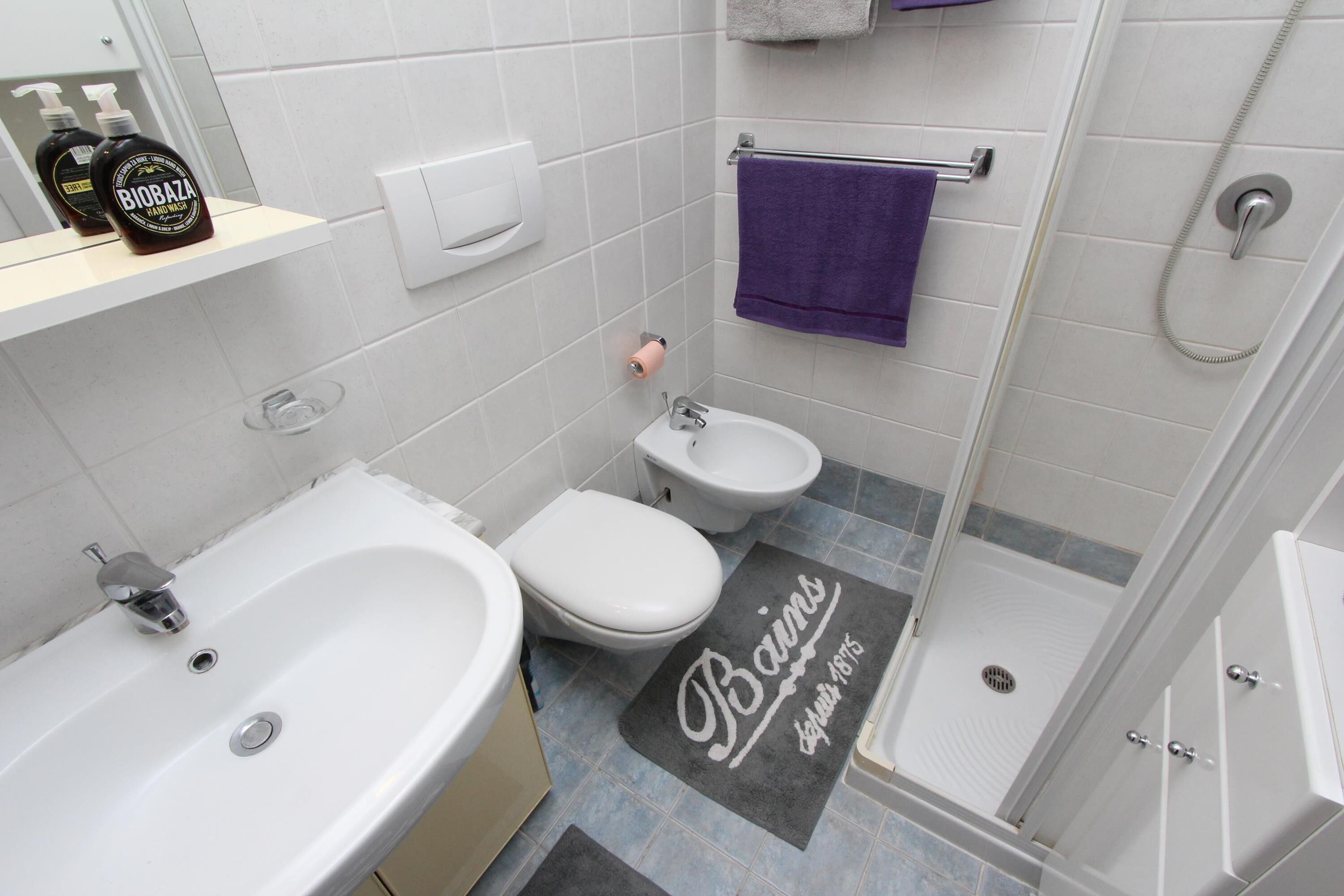 A modern bathroom with a bathtub, a toilet, and a shower.