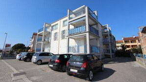 A multi-story residential building with balconies and a parking area in front. - Apartment Ala (Rovinj)